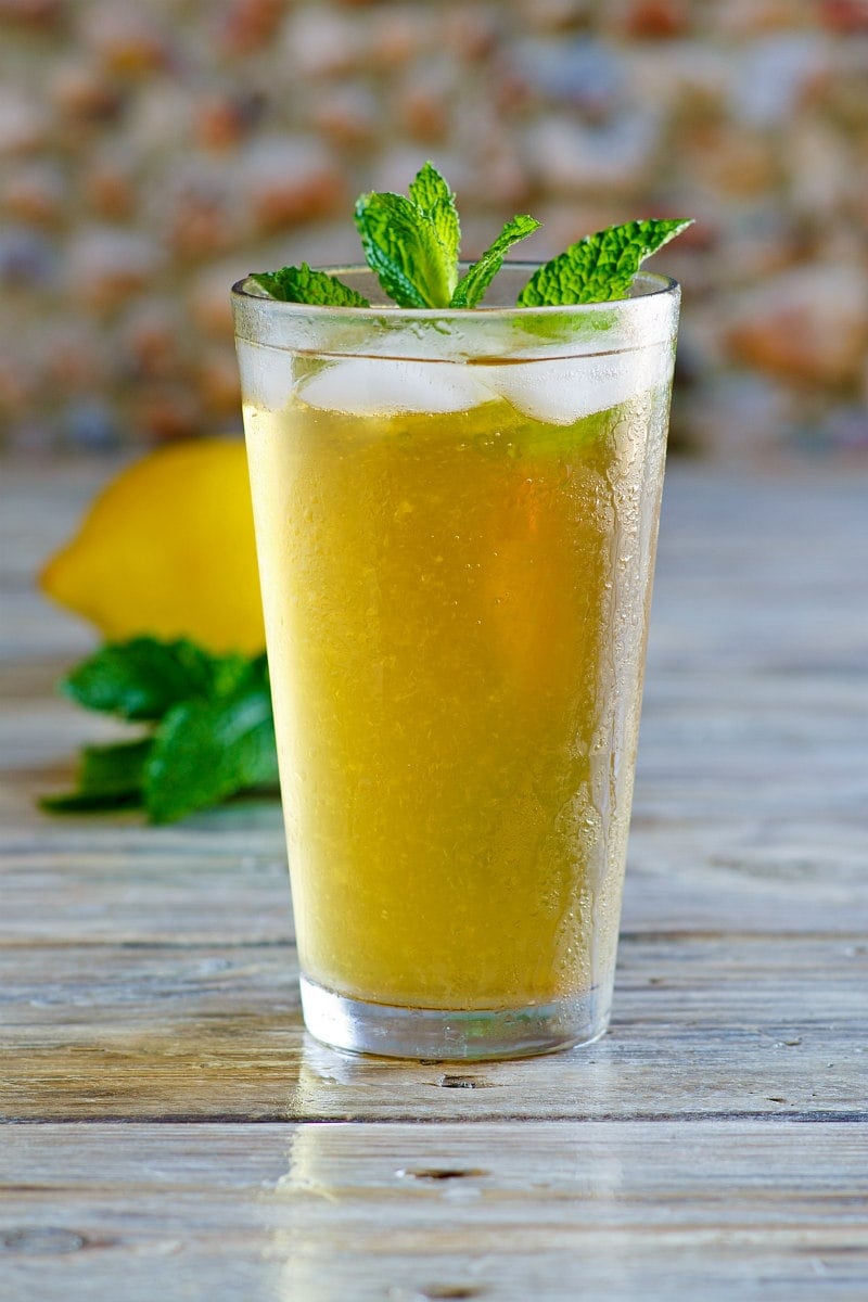 Sweet Summer Iced Tea garnished with fresh mint with a fresh lemon in the background