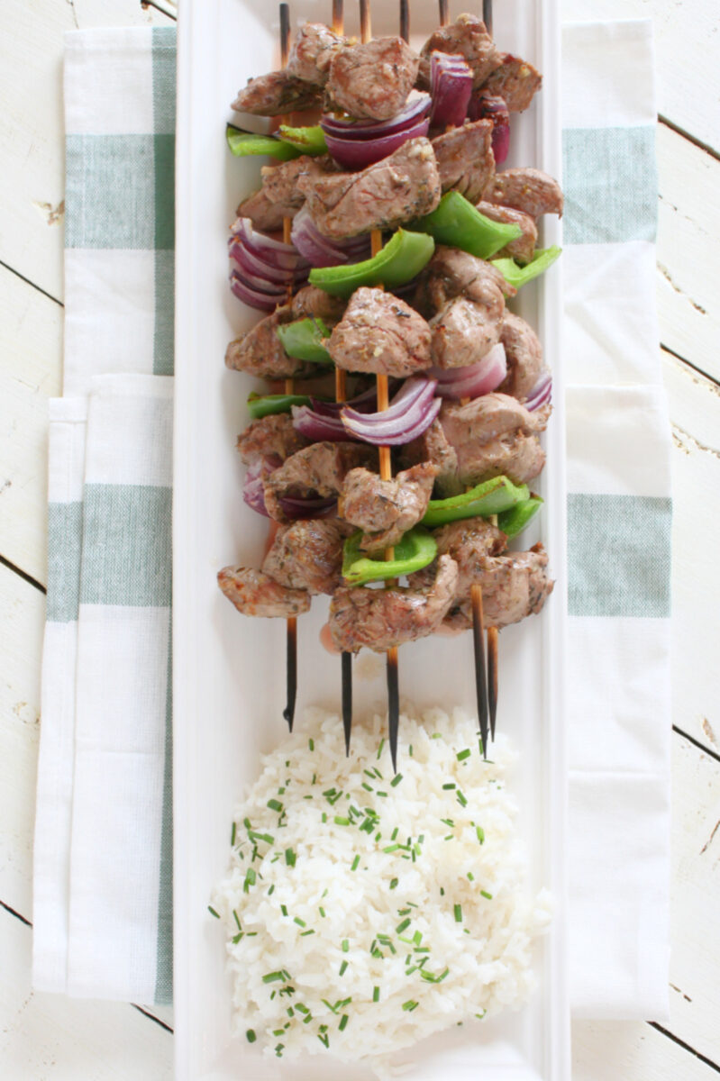 lamb souvlaki with rice on a white platter