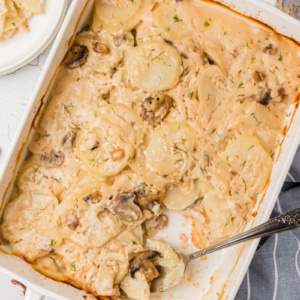 spoon in casserole dish of mushroom dill scalloped potatoes