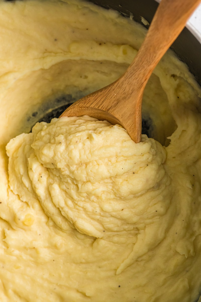 mustard mashed potatoes in a pan with a wooden spoon
