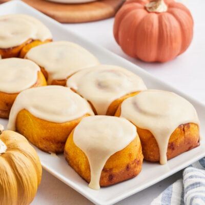 pumpkin cinnamon rolls with maple icing on a white platter