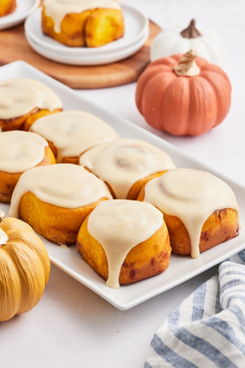 pumpkin cinnamon rolls with maple icing on a white platter