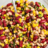 Red White and Black Bean Salad in a glass bowl with a spoon