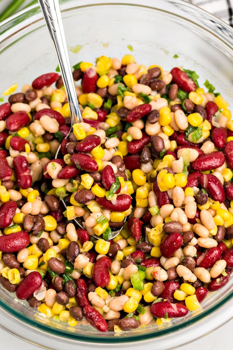 Red White and Black Bean Salad in a glass bowl with a spoon