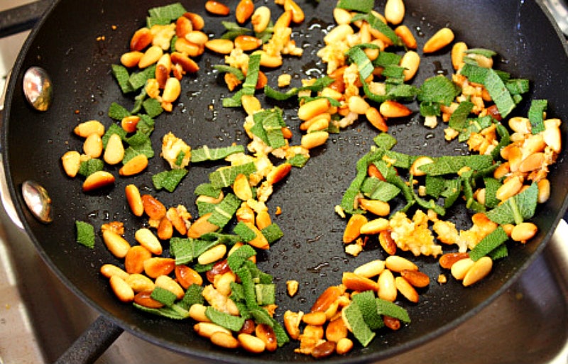 sage and pine nuts in a skillet