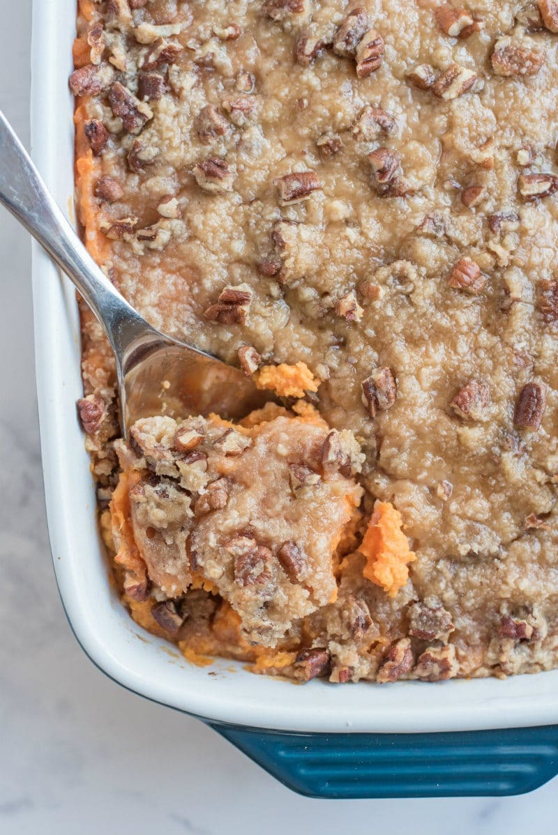 streuseled sweet potatoes in white dish with serving spoon taking some out