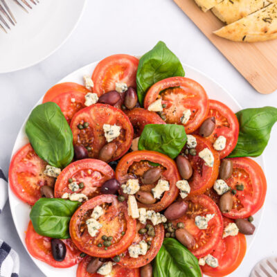 tomato caper and blue cheese salad on a white platter