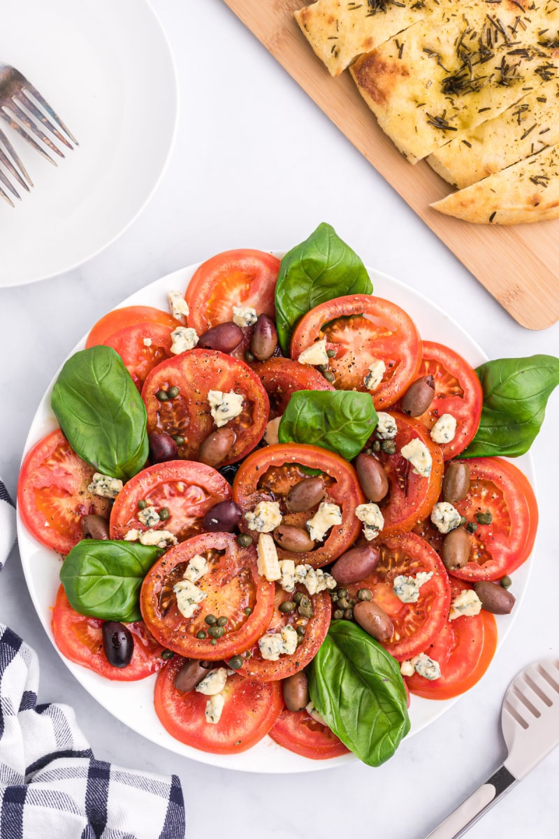 tomato caper and blue cheese salad on a white platter
