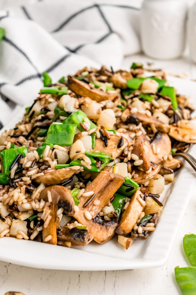 wild rice with snow peas and mushrooms on a white platter