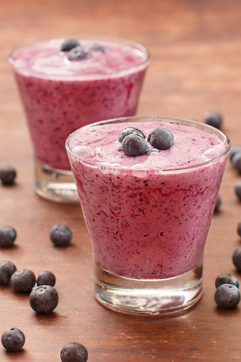 Two blueberry smoothies in glasses, garnished with fresh blueberries