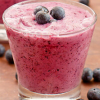 blueberry lemon smoothie in a glass garnished with fresh blueberries and more fresh blueberries scattered around