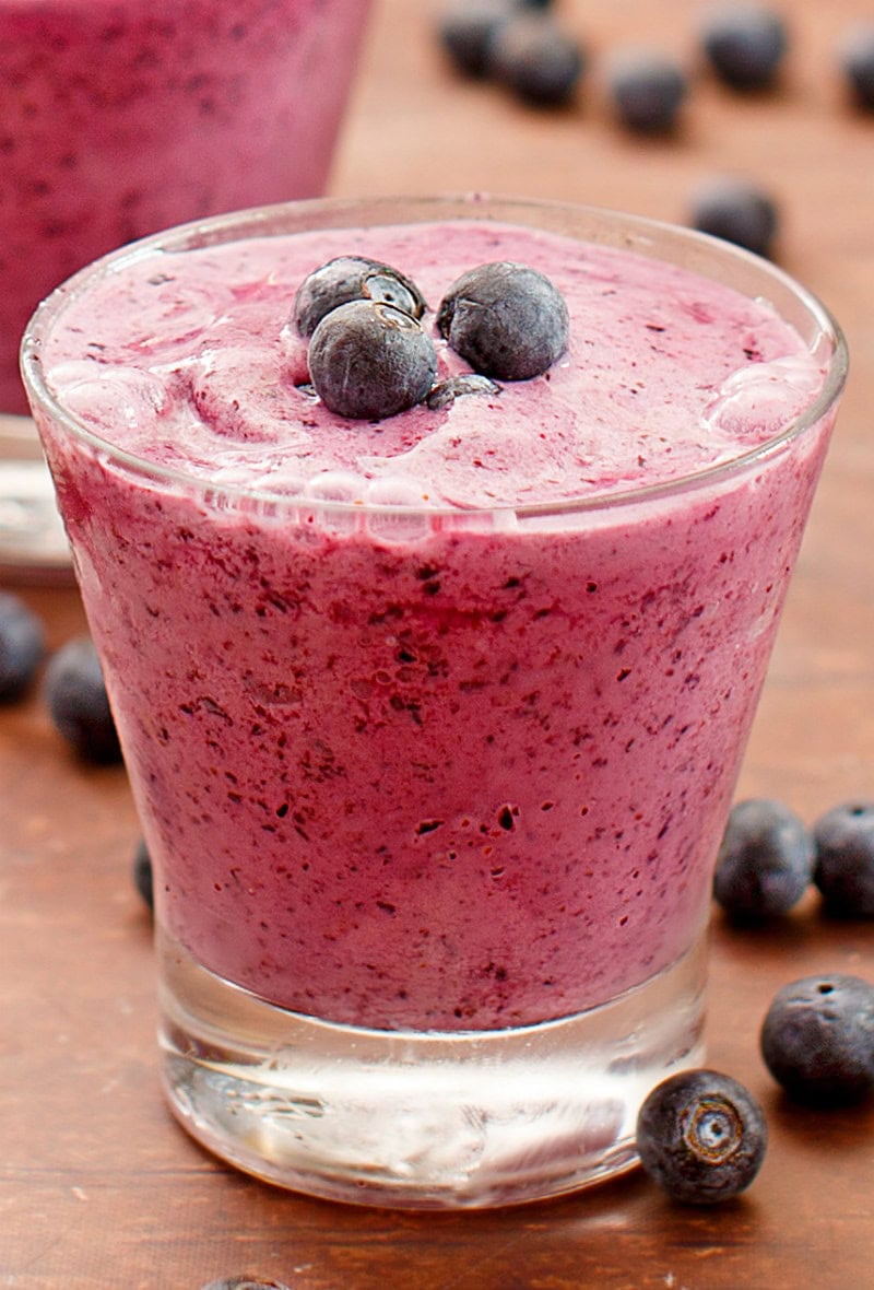 blueberry lemon smoothie in a glass garnished with fresh blueberries and more fresh blueberries scattered around