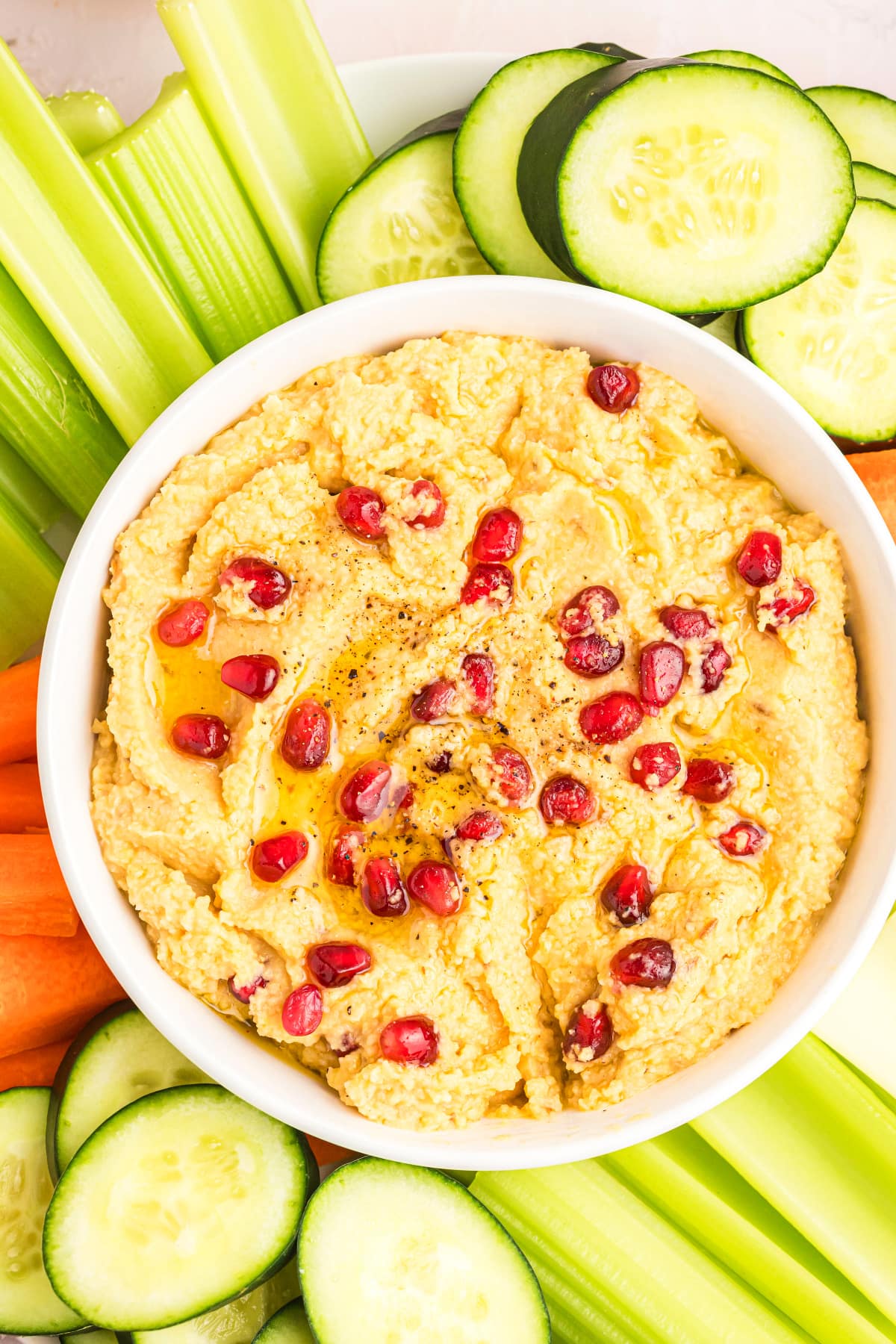 chickpea dip topped with pom seeds and veggies on side