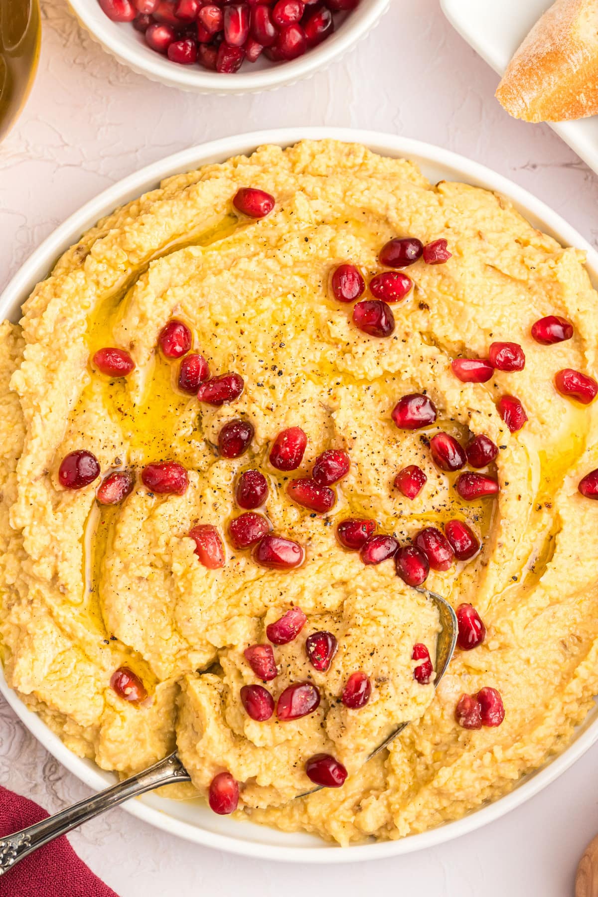 chickpea dip in a bowl topped with pom seeds