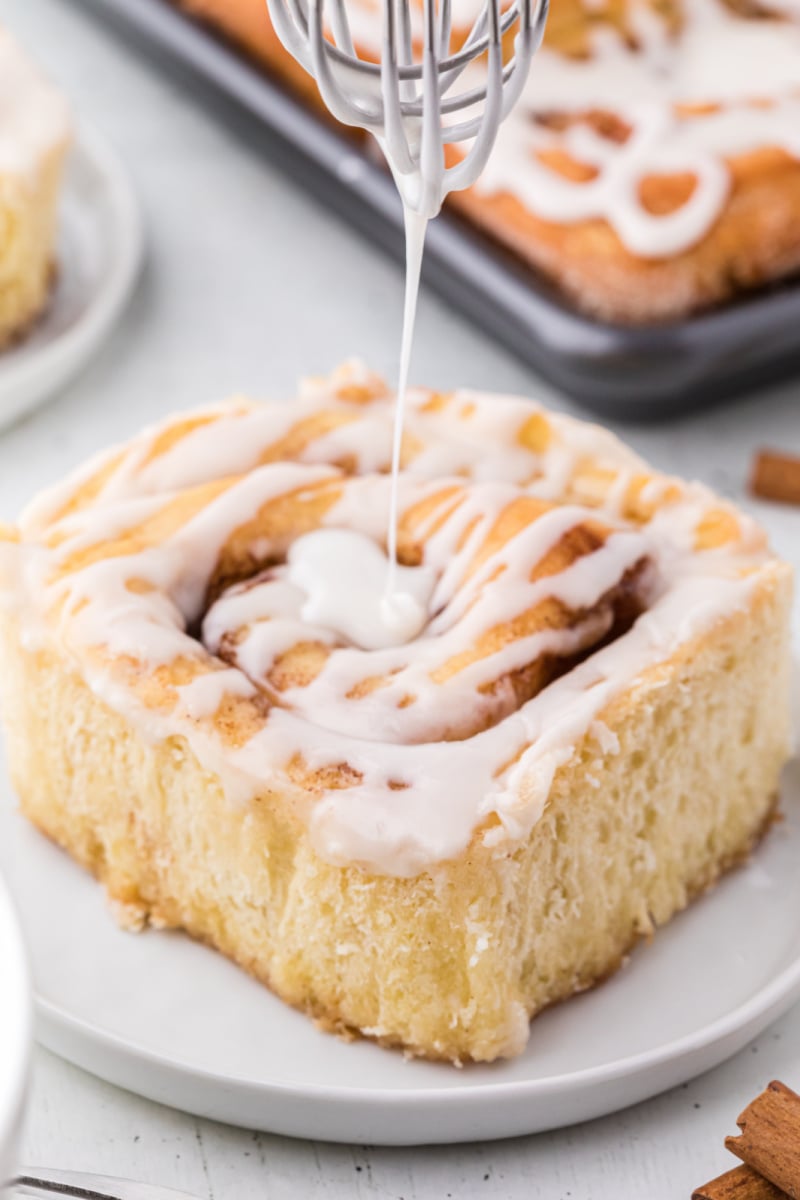 pouring icing onto a cinnamon roll