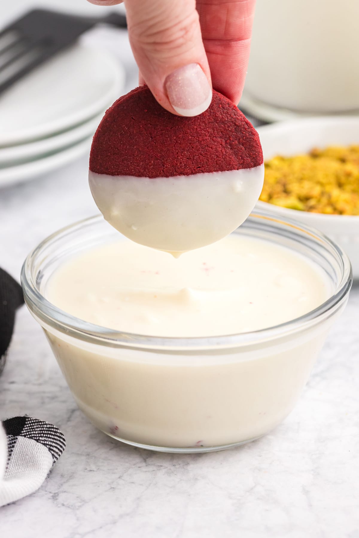 dipping a red velvet shortbread cookie in white chocolate