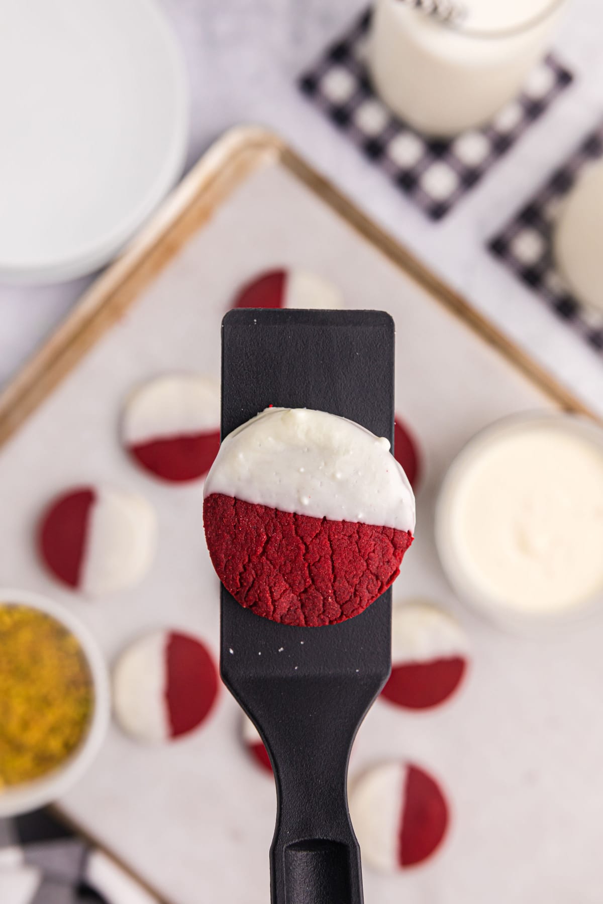 spatula holding red velvet shortbread cookie dipped in white chocolate