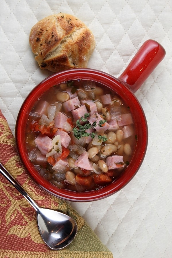 Smoked Ham Soup in a red bowl with spoon and dinner roll