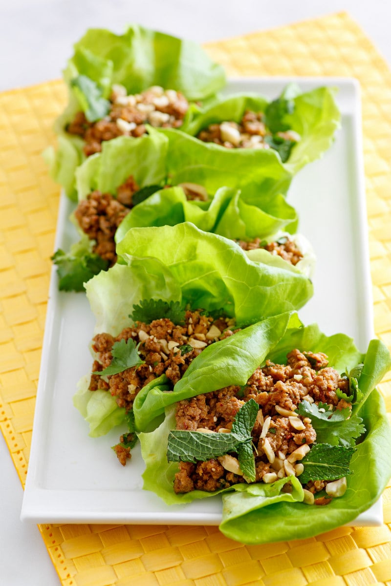 asian lettuce wraps on a white plate set on a yellow napkin