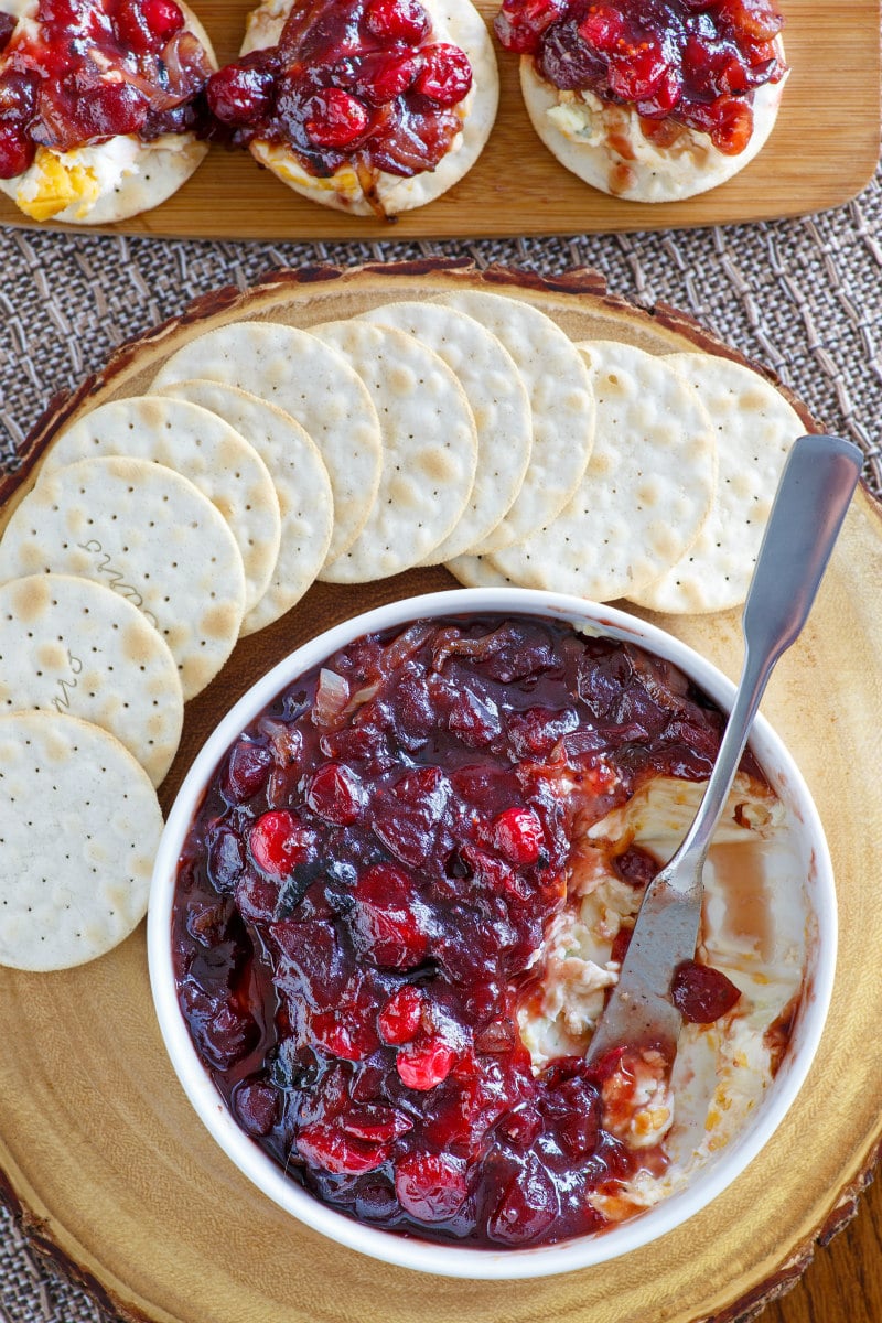 Dish of Cranberry Caramelized Onion Cheese Spread on a serving board served with crackers