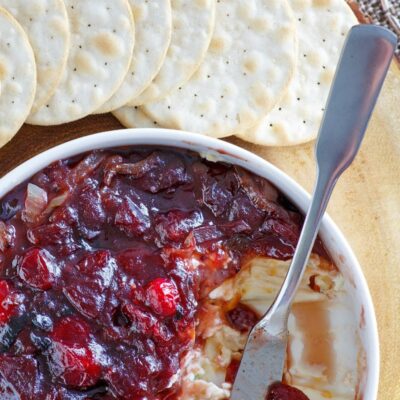 close up of white bowl of cranberry cheese spread served with crackers