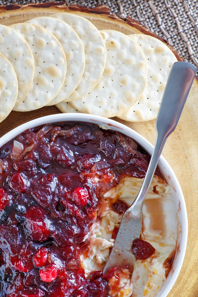 close up of white bowl of cranberry cheese spread served with crackers