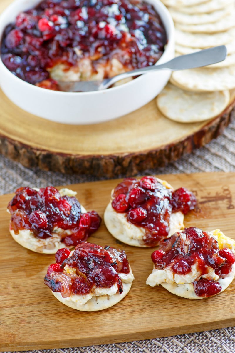 crackers with cranberry spread displayed on a wooden boar