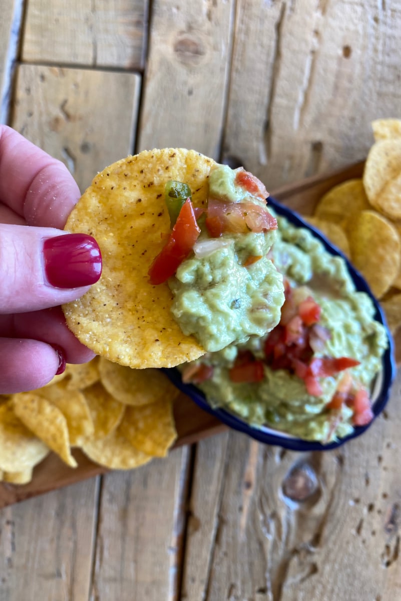 hand holding chip with guacamole on it