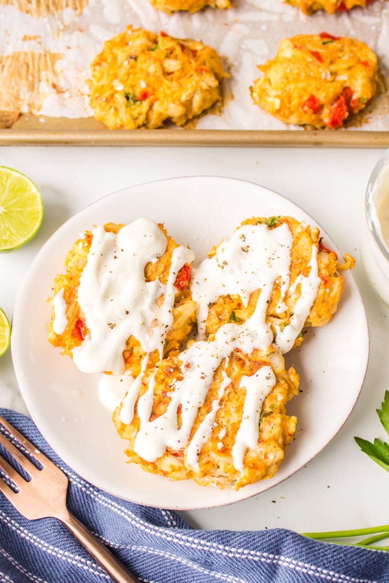 three crab cakes on a plate drizzled with sauce