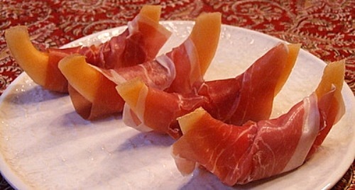 four prosciutto wrapped melon on a plate