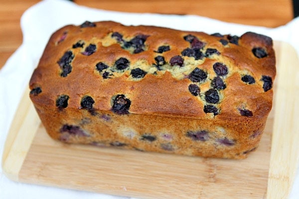 loaf of Banana Blueberry Bread sitting on a cutting board