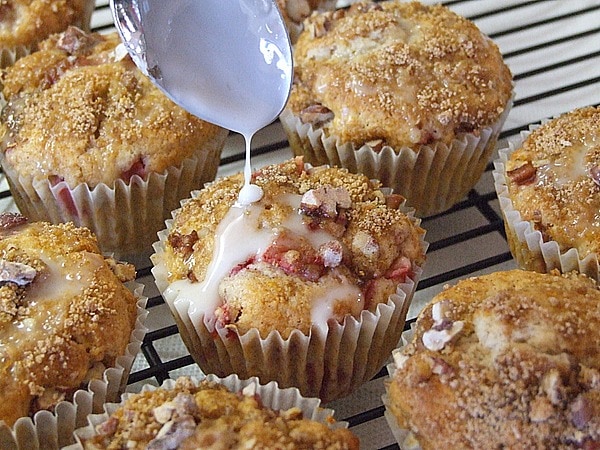 drizzling glaze onto streusel topped strawberry muffins