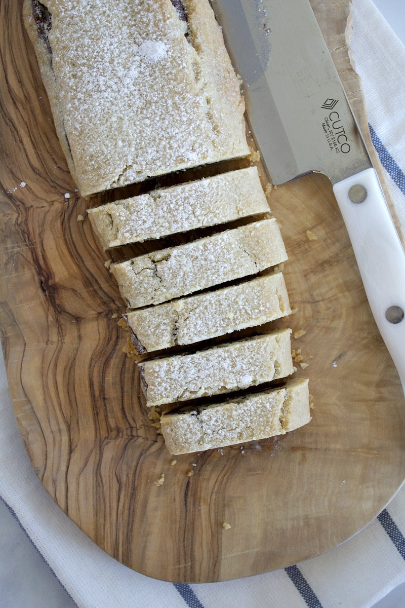 overhead shot of bar of bake and slice cookies on a cutting board with a knife- sliced into pieces