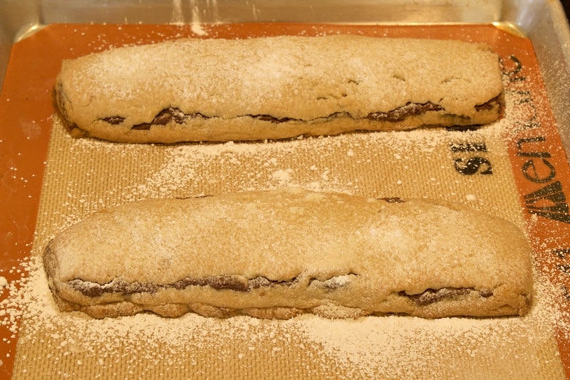 two bake and slice chocolate swirl cookie bars on a baking sheet with powdered sugar sprinkled on top