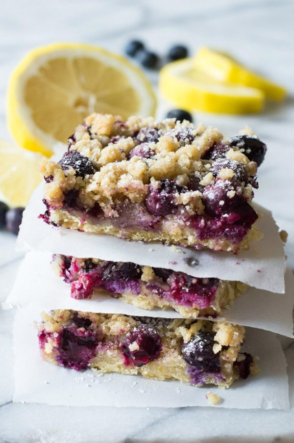 stack of Blueberry Lemon Crumb Bars with fresh cut lemons in the background
