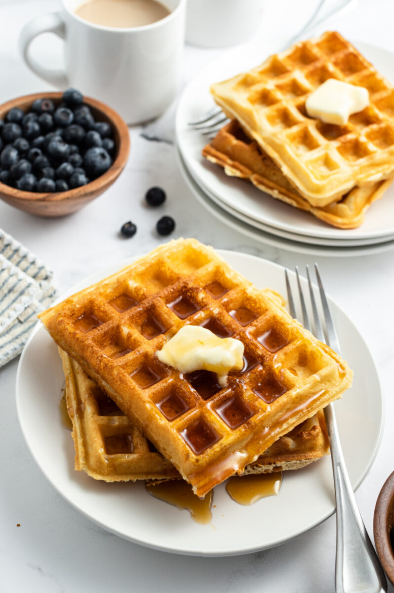 waffles stacked on plate with butter and syrup