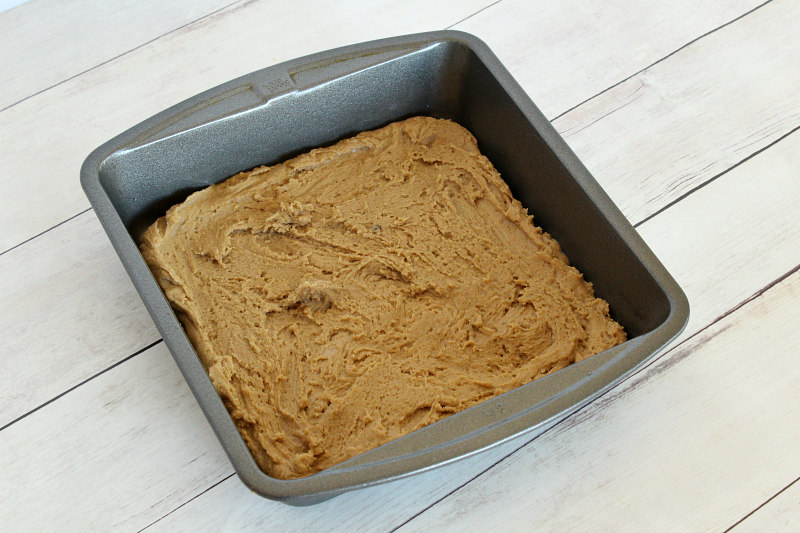 batter for butterscotch brownies spread into a square pan sitting on a white wood background