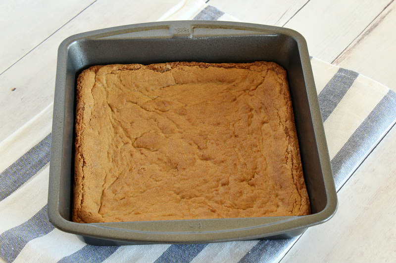 square pan of butterscotch brownies on a blue and white striped cloth towel