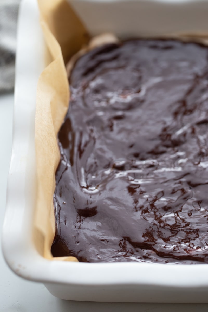 frosting added to brownies in a pan