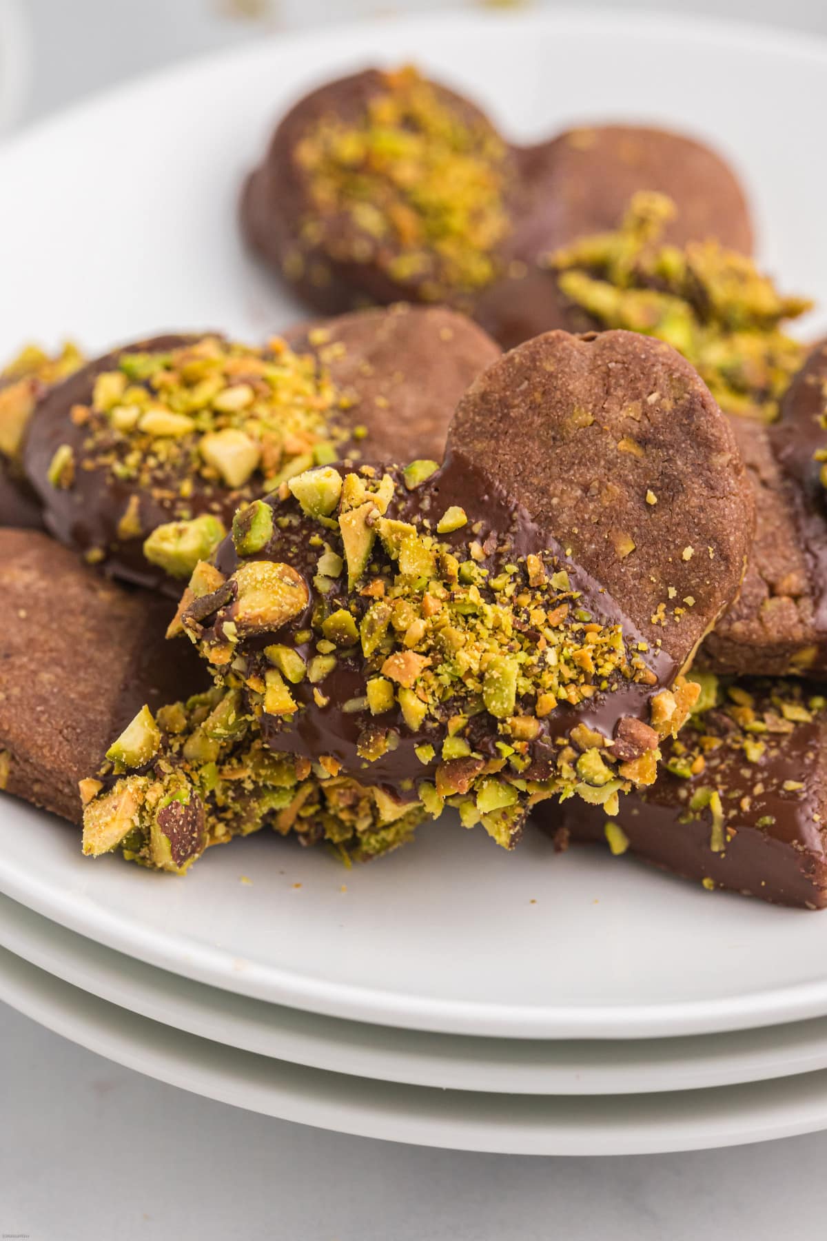 chocolate pistachio cut out cookies dipped in pistachios on plates