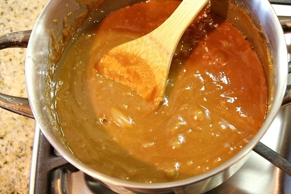 pan of hot toffee for almond roca stirring with wooden spoon