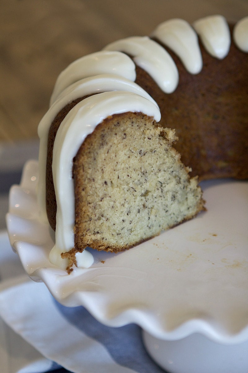 banana bundt cake on a white serving platter. Cake is cut into to see the inside.