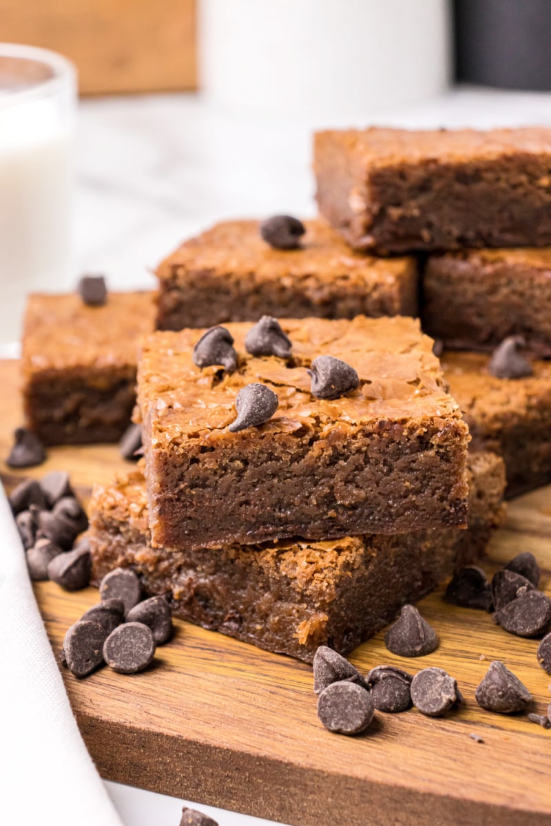 brownies stacked on a cutting board with scattered chocolate chips