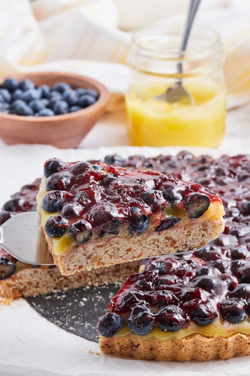 spatula taking out slice of blueberry lemon tart