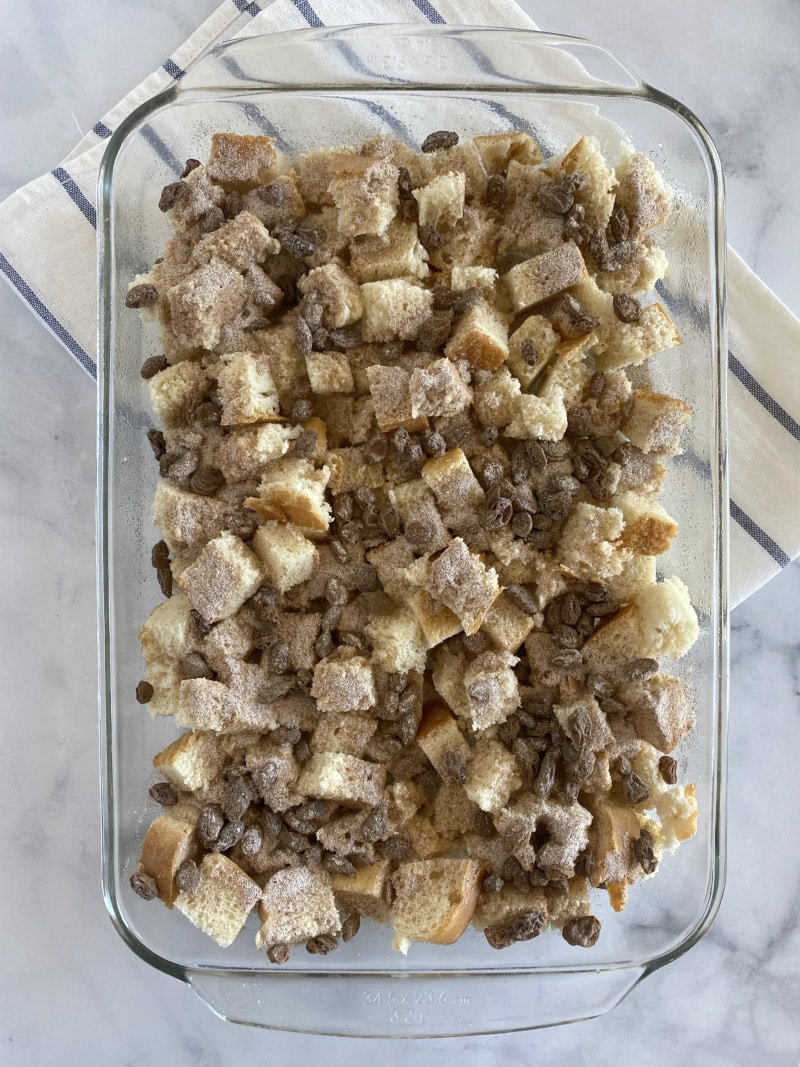 making bread pudding- putting bread cubes and topping in a casserole dish