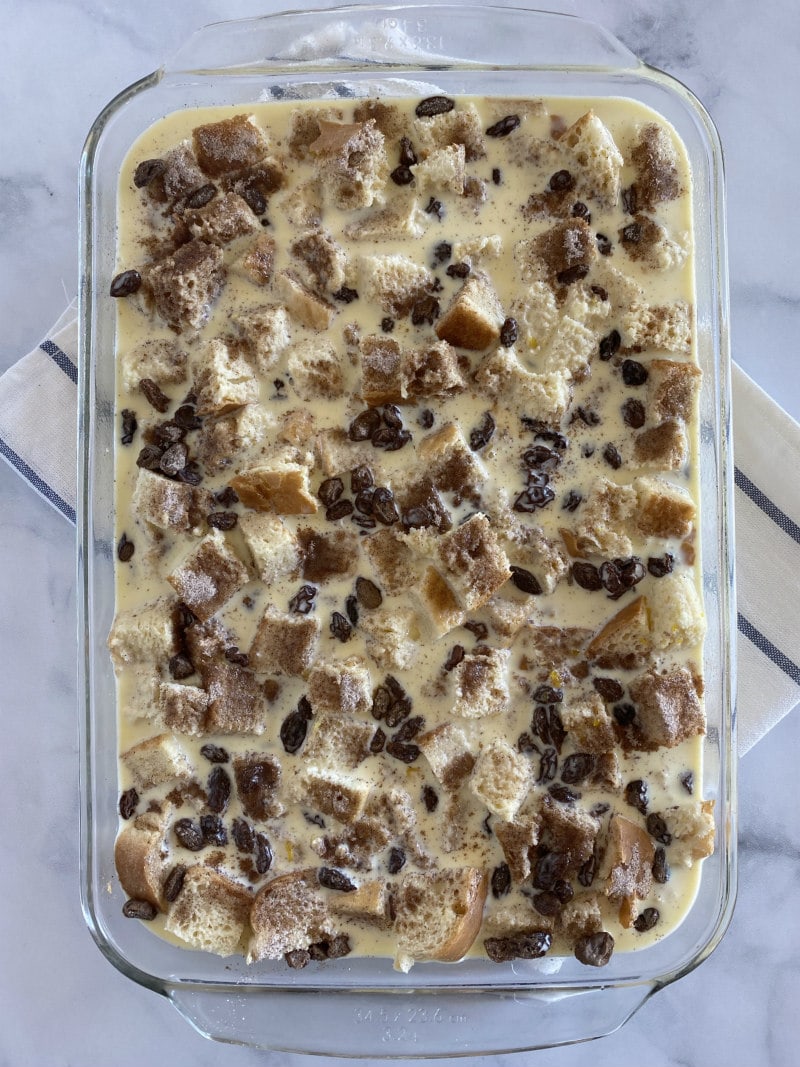 making bread pudding- adding the egg custard to bread cubes in a baking dish