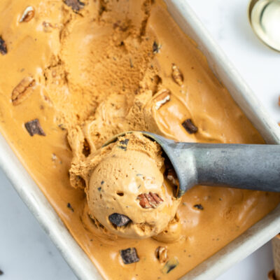 caramel chocolate nut ice cream in a tub with a scoop