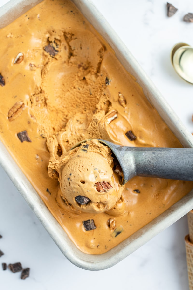 caramel chocolate nut ice cream in a tub with a scoop