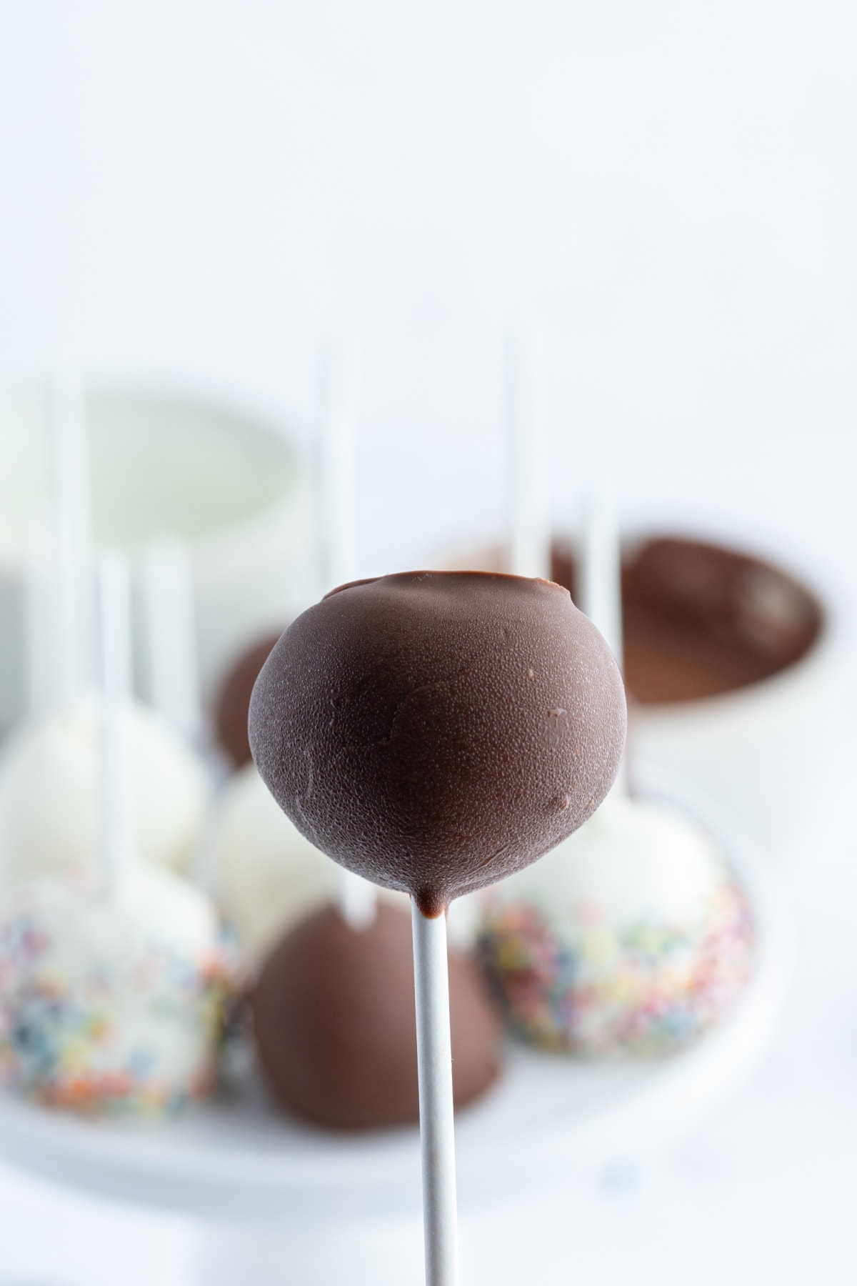holding up chocolate covered cheesecake pop