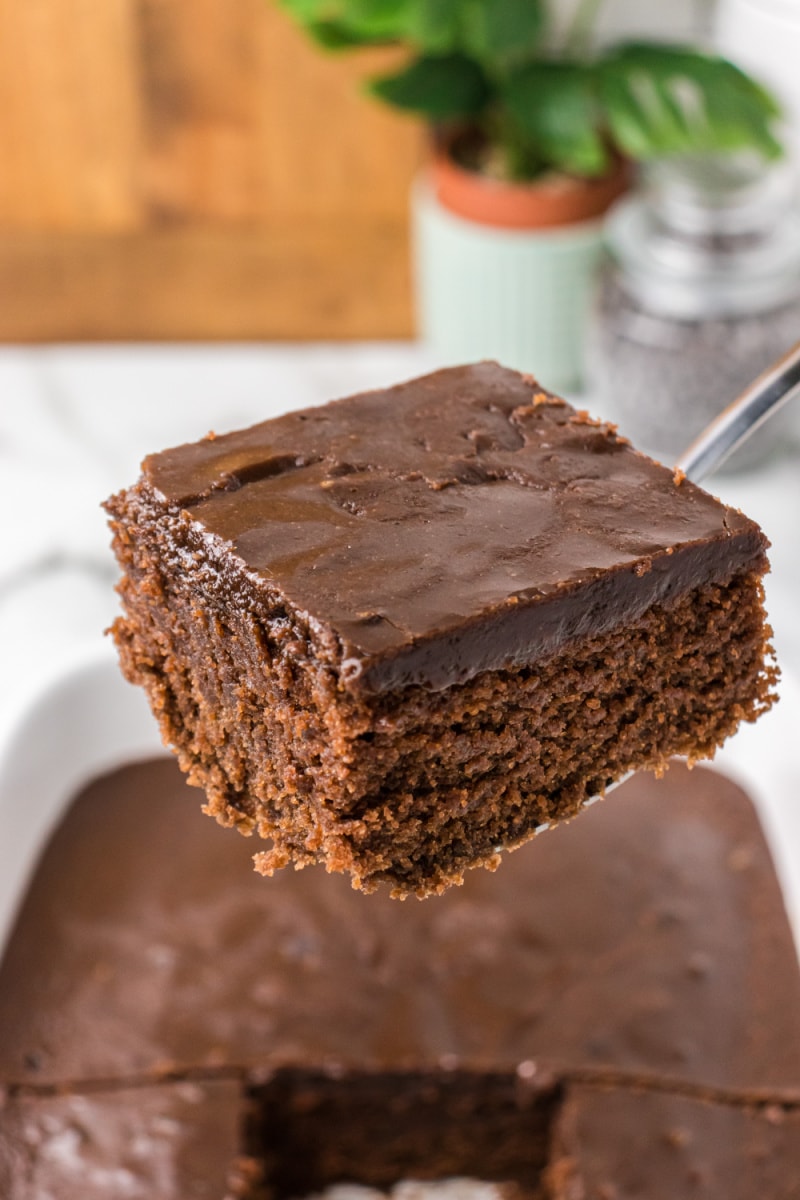 spatula holding up slice of chocolate glazed cake